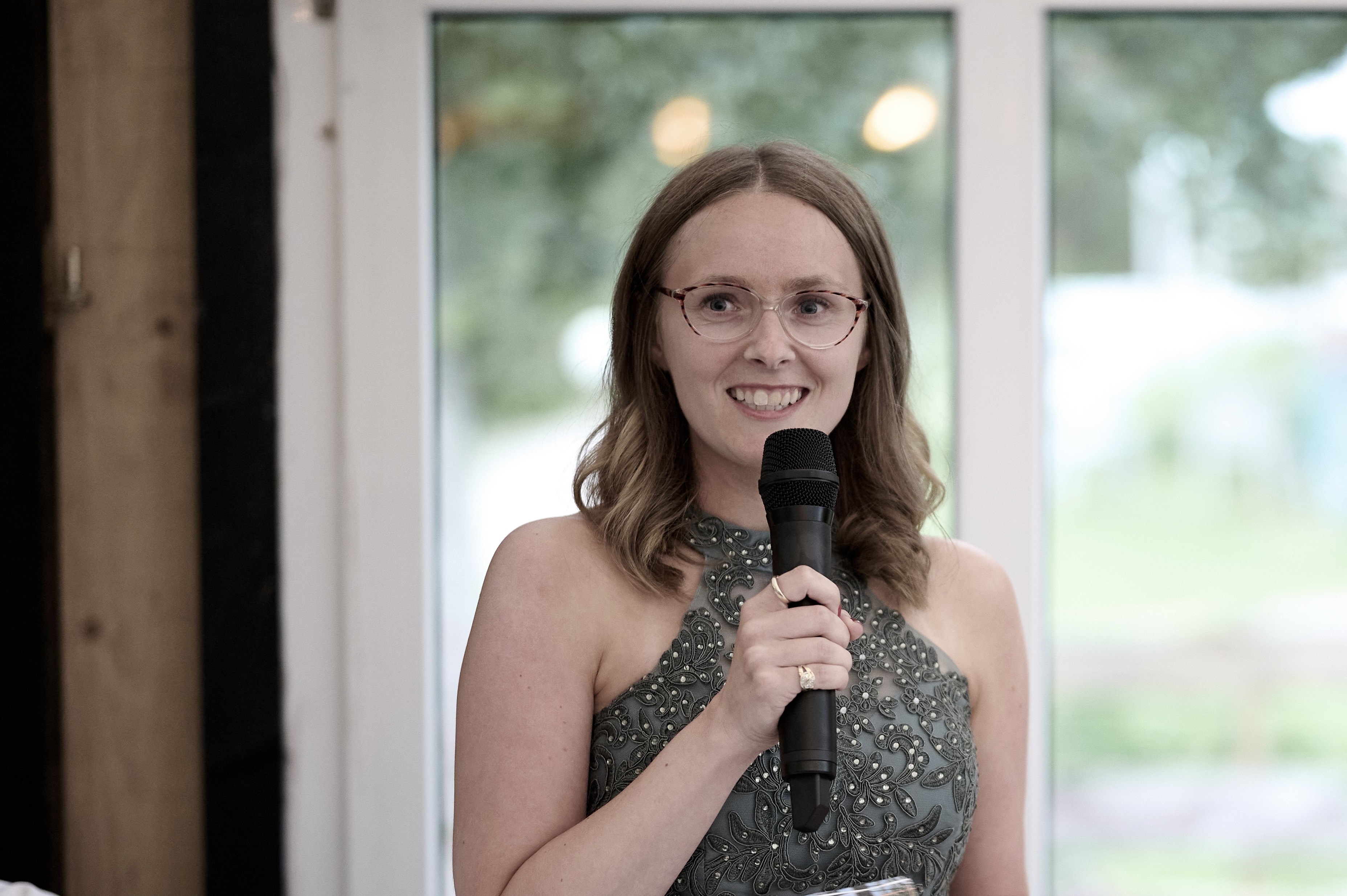 Liza Kummrow, Gründerin von Mitten ins Herz hält eine Rede mit Mikrofon und lädt zur Kooperation für emotionale Podcast-Geschenke ein. Egal ob für Hochzeiten, Jubiläen oder Geburtstage - jede:r Content Creator:in und jeder Mitten ins Herz Affiliate Partner:in ist Herzlich Willkommen. Liza freut sich auf die Zusammenarbeit.